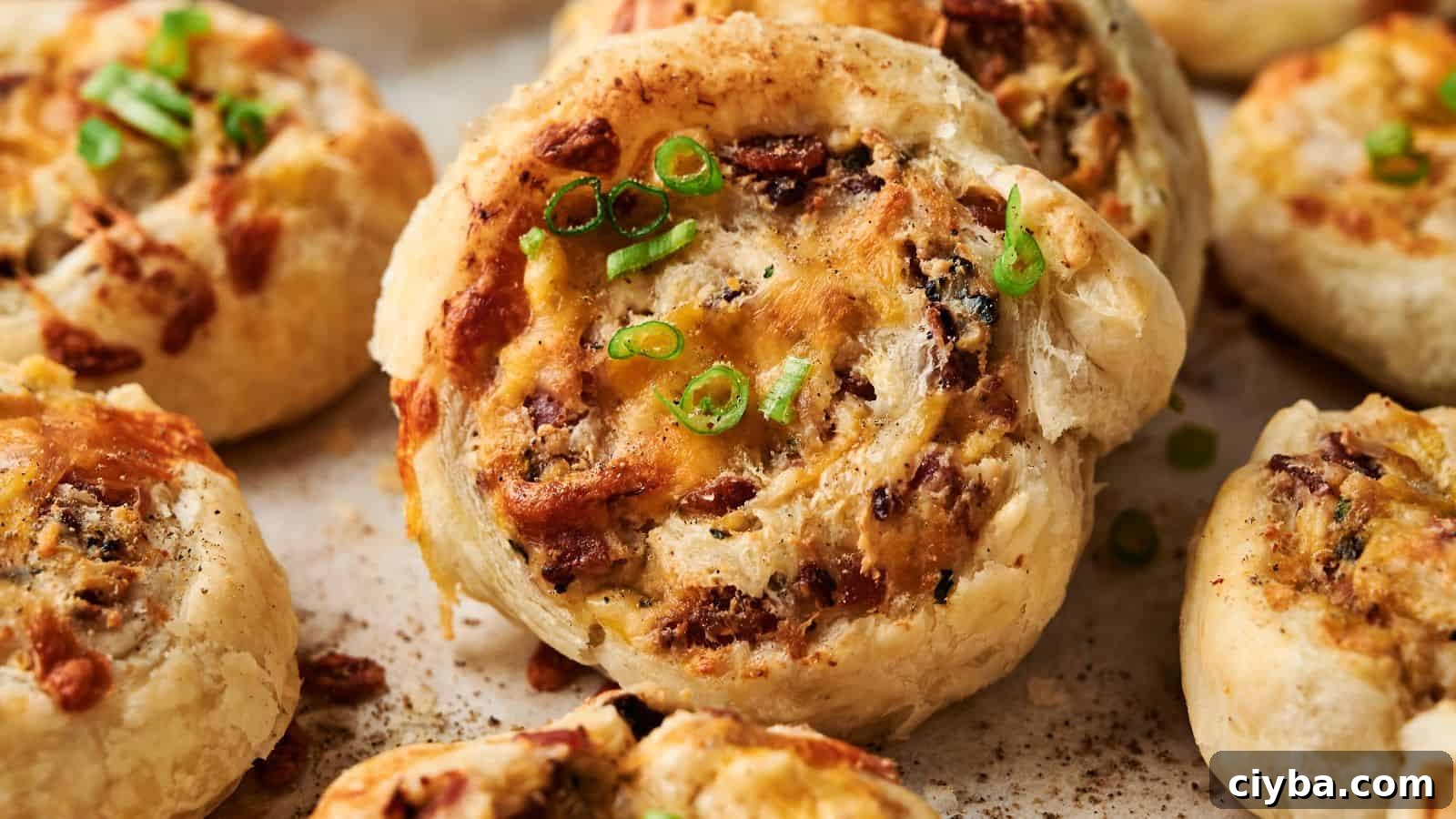 Close-up of baked puff pastry pinwheels filled with cheese, herbs, and finely chopped toppings, garnished with sliced green onions.