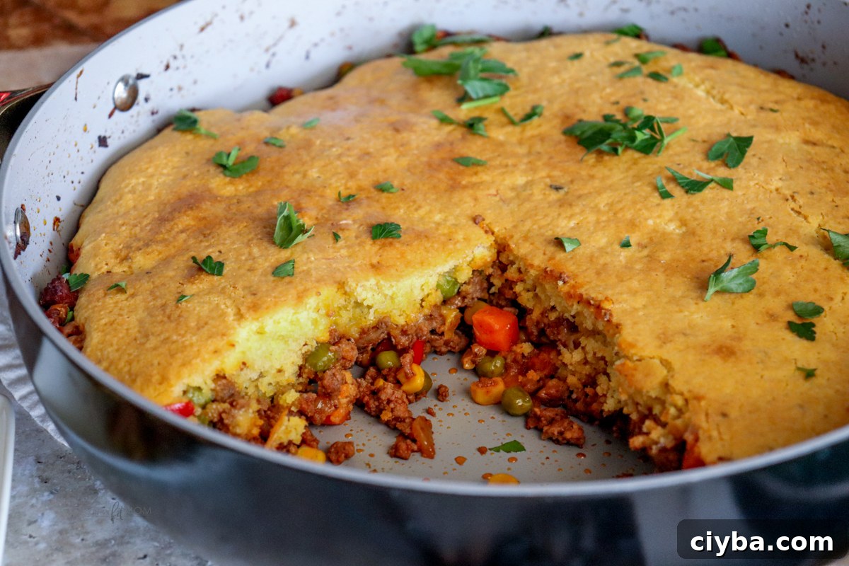 Hearty Cowboy Cornbread Casserole Bake 6 Cowboy Cornbread Casserole showing pan with one piece missing showing cornbread and casserole filling.