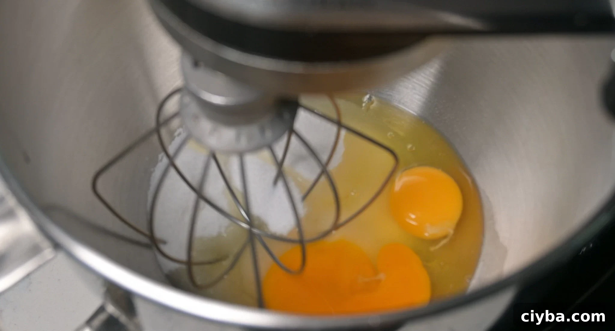 Sugar and eggs in the bowl of a stand mixer.