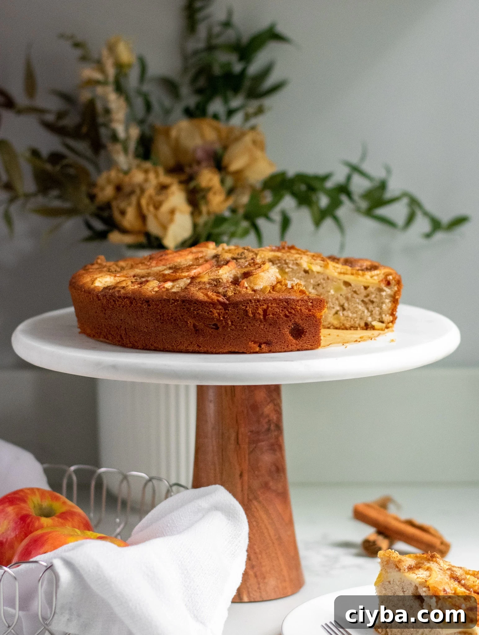Apple cake on a cake stand topped with cinnamon and brown sugar.