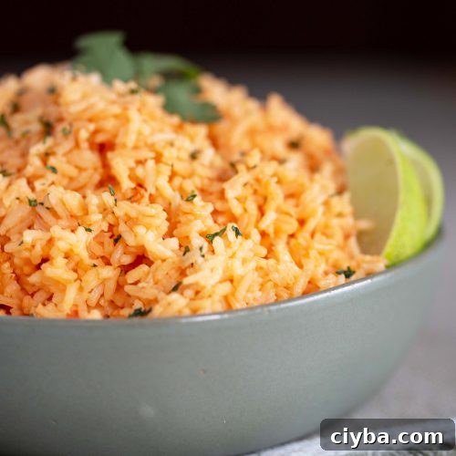 Mexican rice in a green bowl, garnished with slices of lime