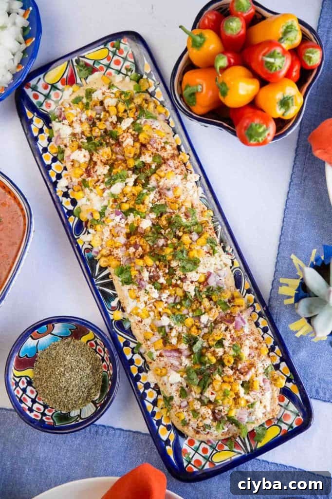 Creamy Mexican Street Corn Dip Recipe for Parties 5 long rectangular platter of mexican street corn dip, surrounded by mini bell peppers.