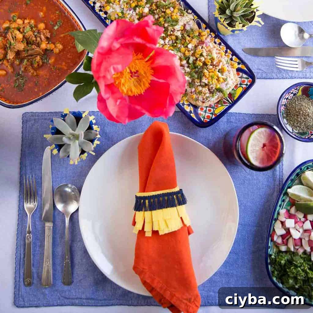 Creamy Mexican Street Corn Dip Recipe for Parties 6 colorful table set for a cinco de mayo celebration, with a blue placemat, orange napkin, and a blue and yellow napkin ring.