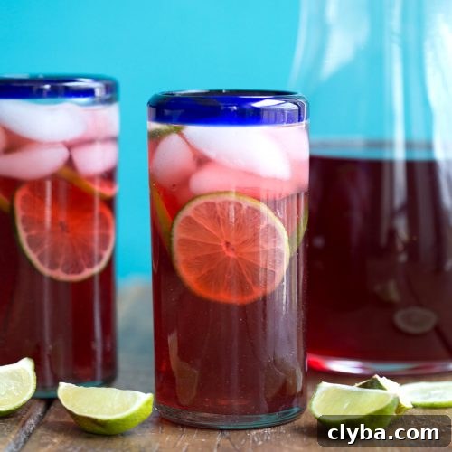 glass of hibiscus iced tea with limes