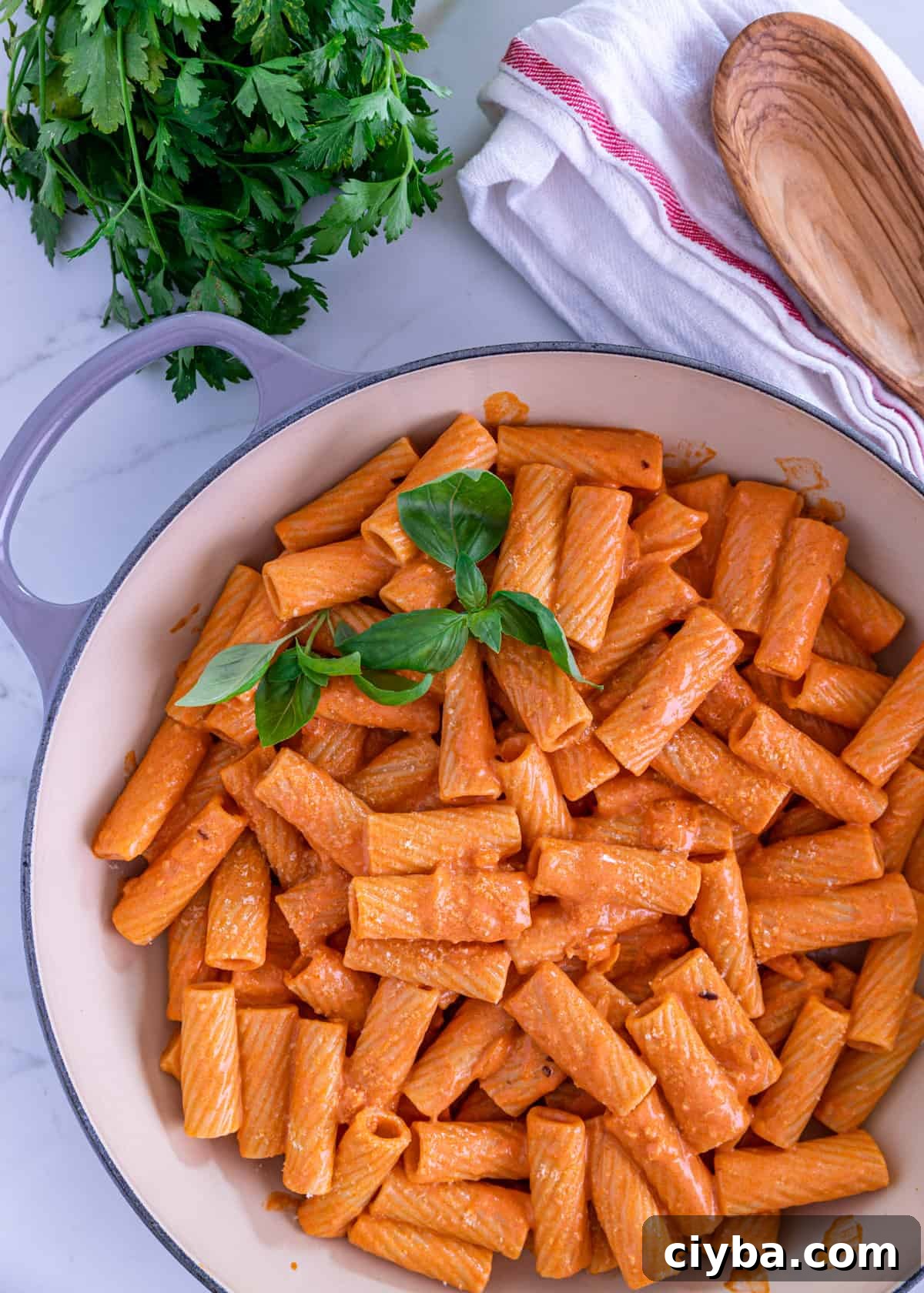 overhead: rigatoni with vodka sauce and fresh basil on top in a large pot