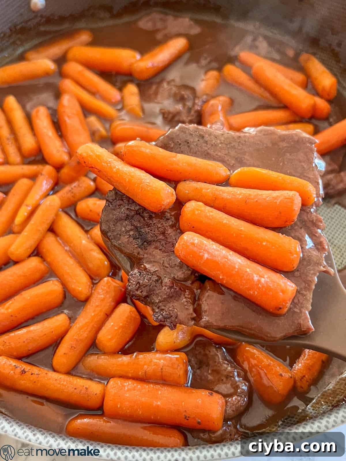 Round steak and gravy with cooked carrots.