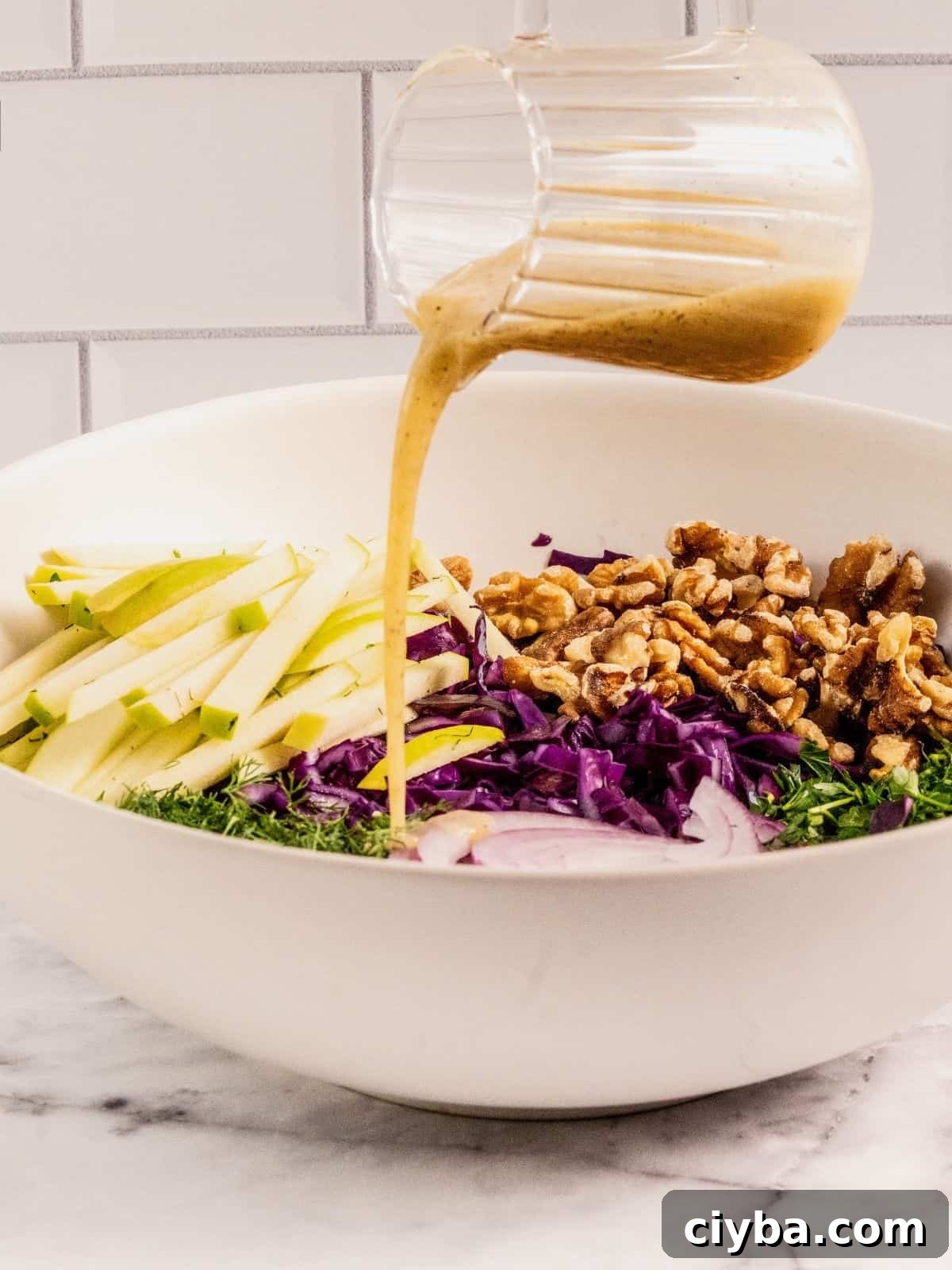 Crisp Purple Cabbage Slaw with Apple and Walnut Crunch 8 Pouring dressing over the salad ingredients.
