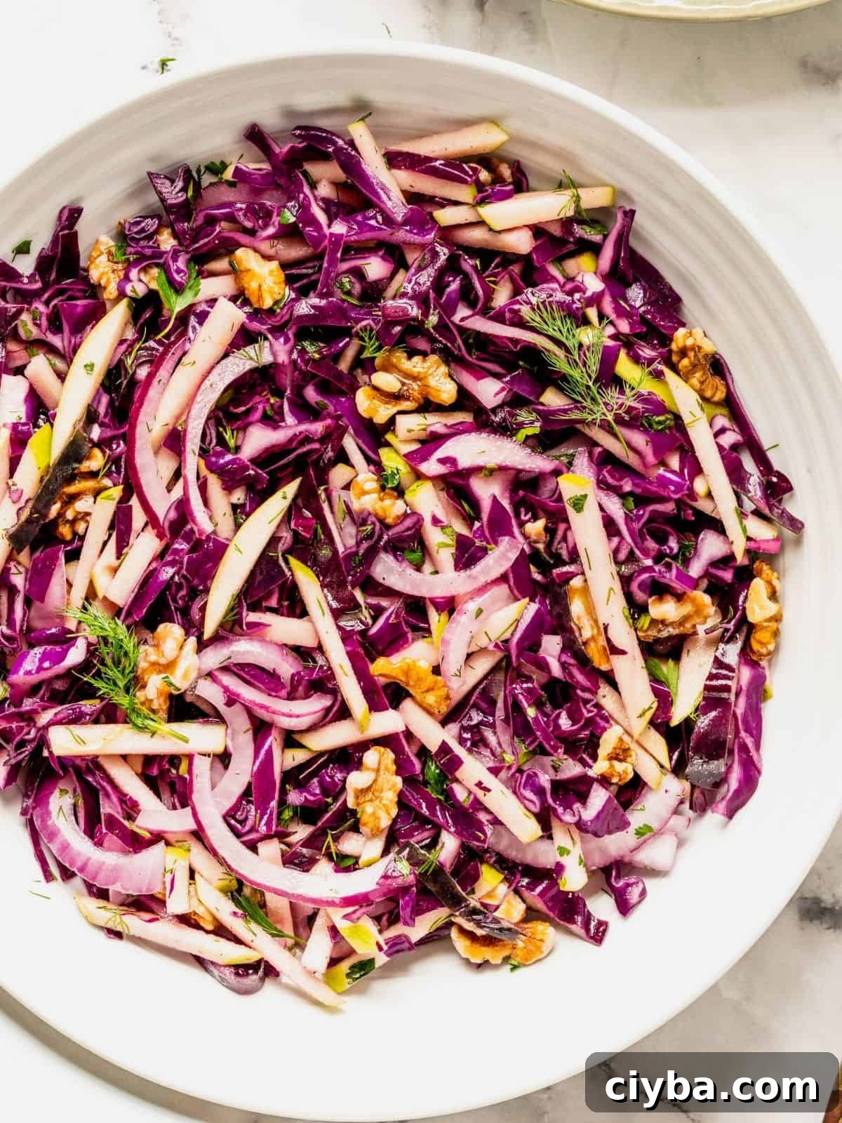 Crisp Purple Cabbage Slaw with Apple and Walnut Crunch 9 Purple cabbage slaw with apples and walnuts in a bowl.