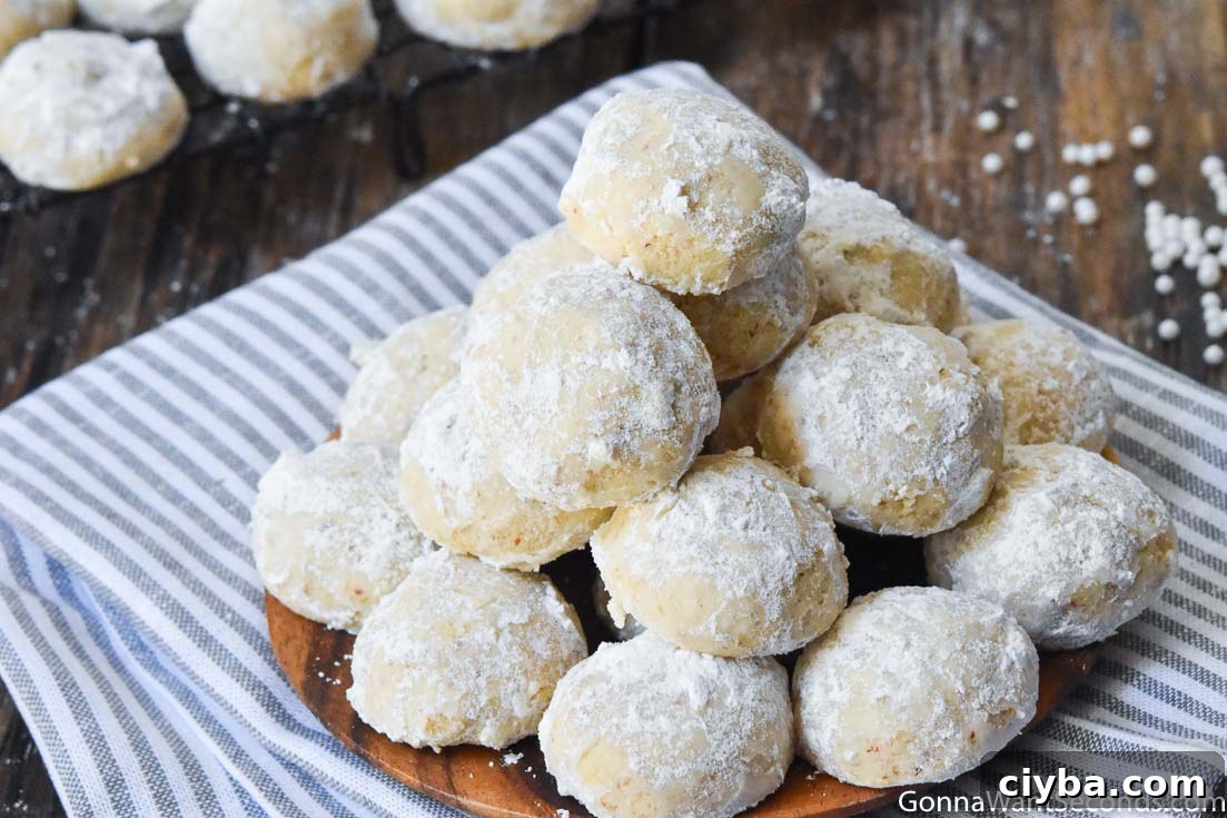 Italian Wedding Cookies dust your dessert trays with confectioner's sugar wonder! A pile of Italian Wedding Cookies on a wooden plate