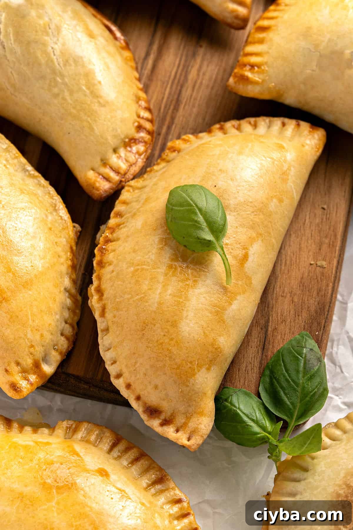 Close up corn empanadas with basil leaves on a wooden board. 