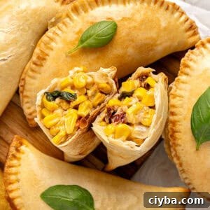 Two corn empanada halves with whole ones. Basil leaves.