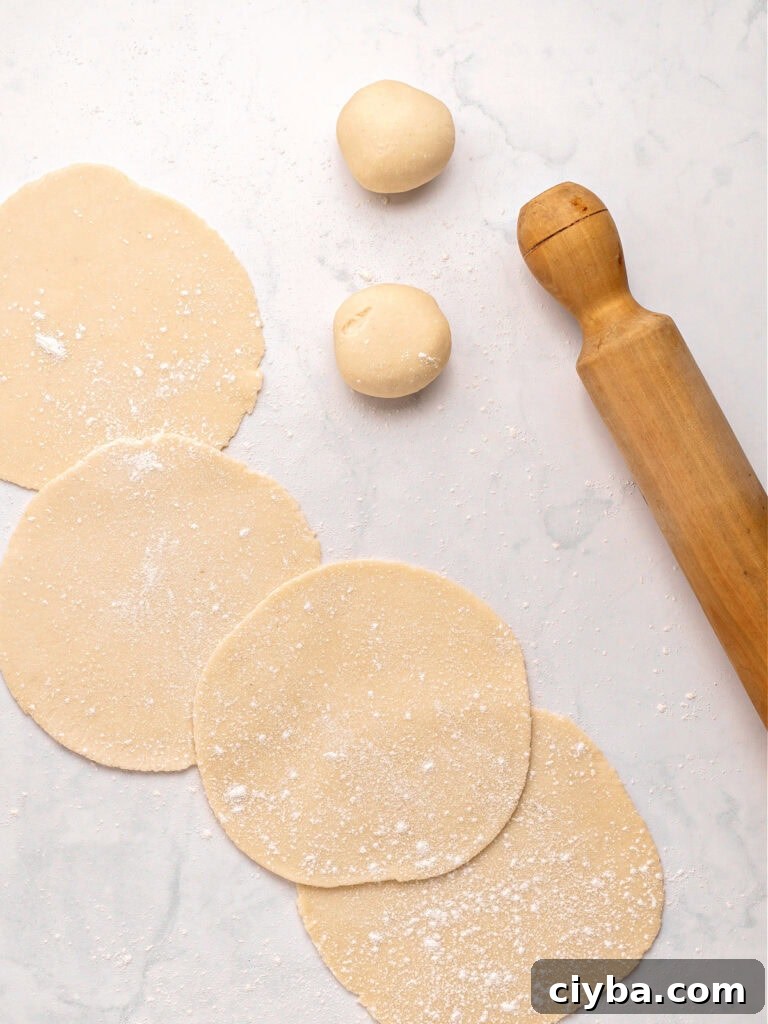 Discs of empanada dough. Rolling pin. Light gray background. 