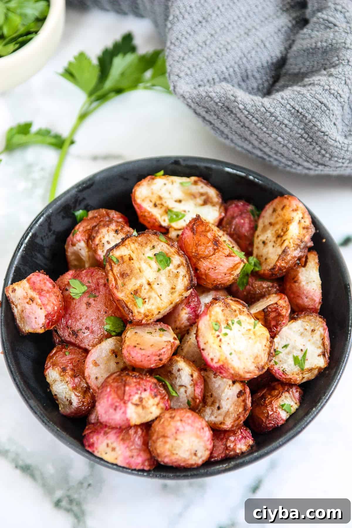 A bowl of air fryer radishes on a marble countertop.