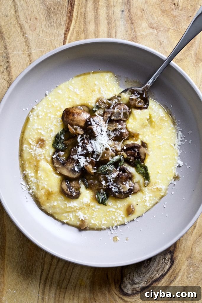 Spoon scooping from a plate of polenta and mushrooms with sage butter sauce.