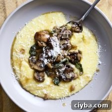 Spoon on a plate with polenta and mushrooms with sage butter sauce.