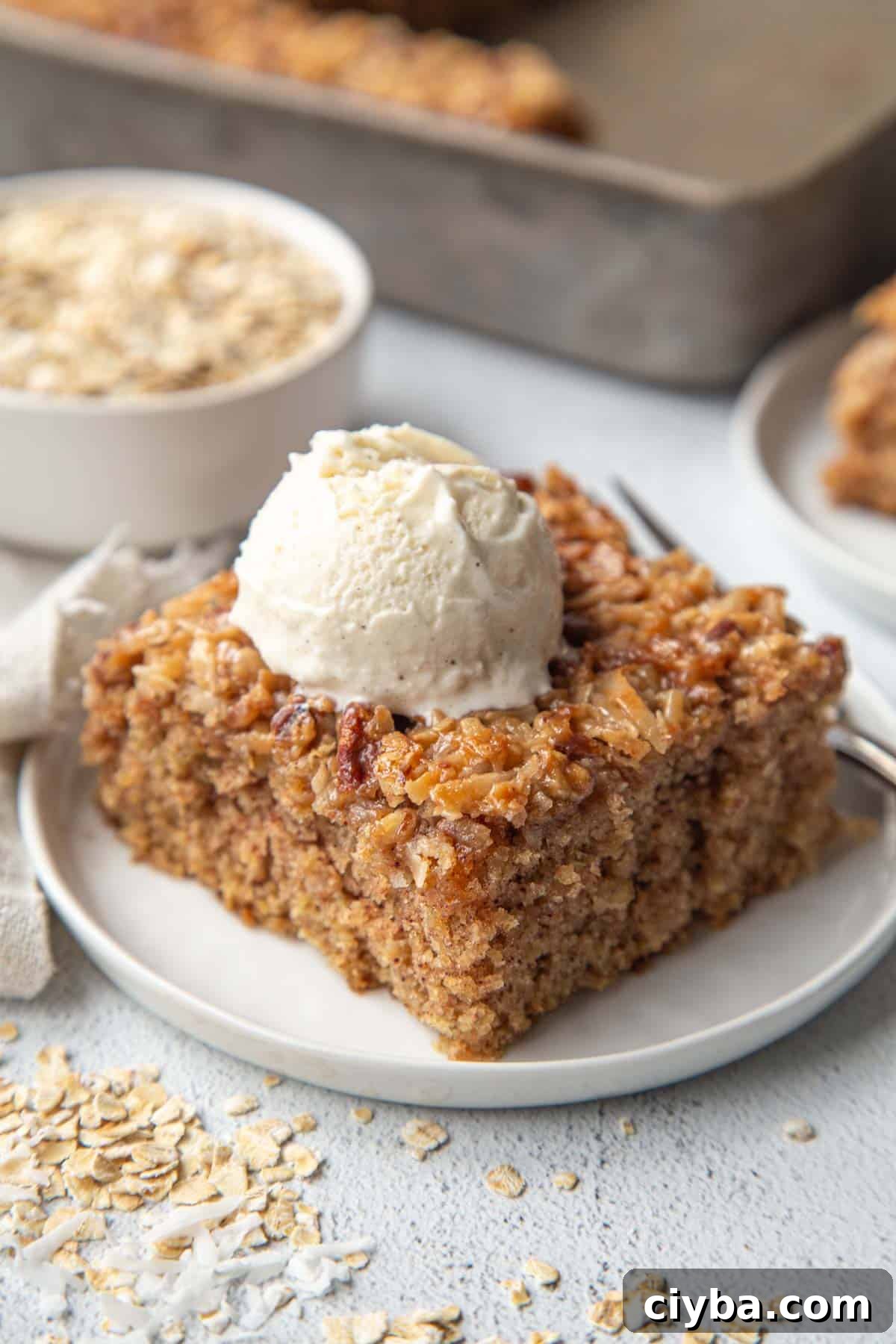 Lazy Daisy Oatmeal Cake Recipe with Cinnamon and Raisins 2 oatmeal cake slice on a white plate, topped with a scoop of vanilla ice cream.