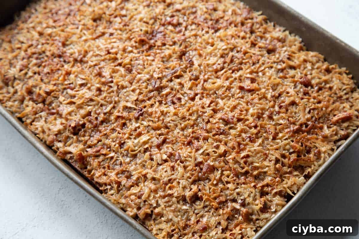 Lazy Daisy Oatmeal Cake Recipe with Cinnamon and Raisins 9 coconut pecan topped oatmeal cake in a metal pan.