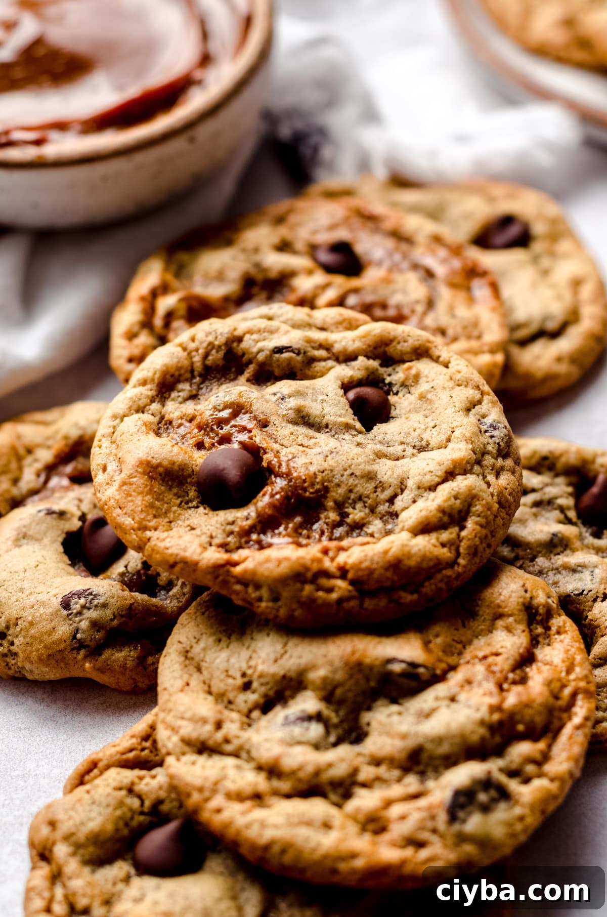 A pile of cookies with a bowl of dulce de leche in the background.