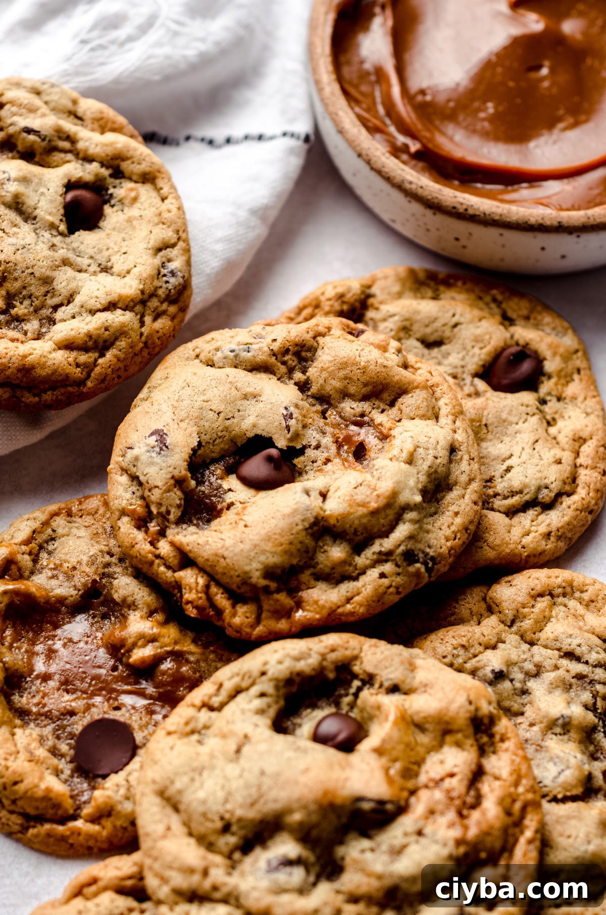A mound of dulce de leche cookies with a bowl of dulce de leche in the background.