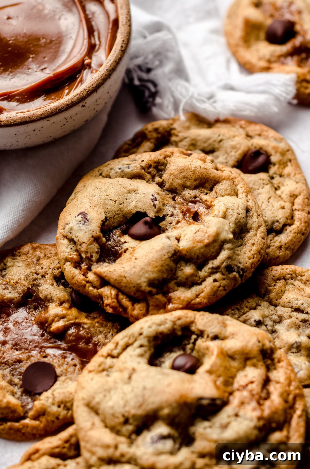 A pile of dulce de leche cookies with a bowl of dulce de leche in the background.