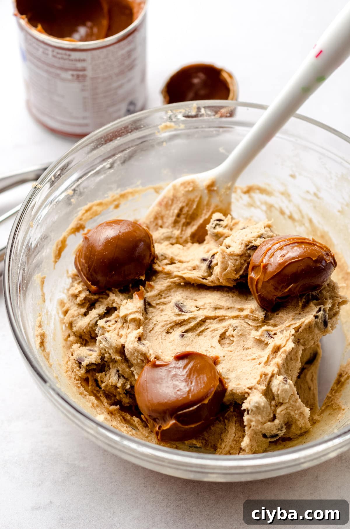 A base cookie dough with 3 large dollops of dulce de leche spread out.