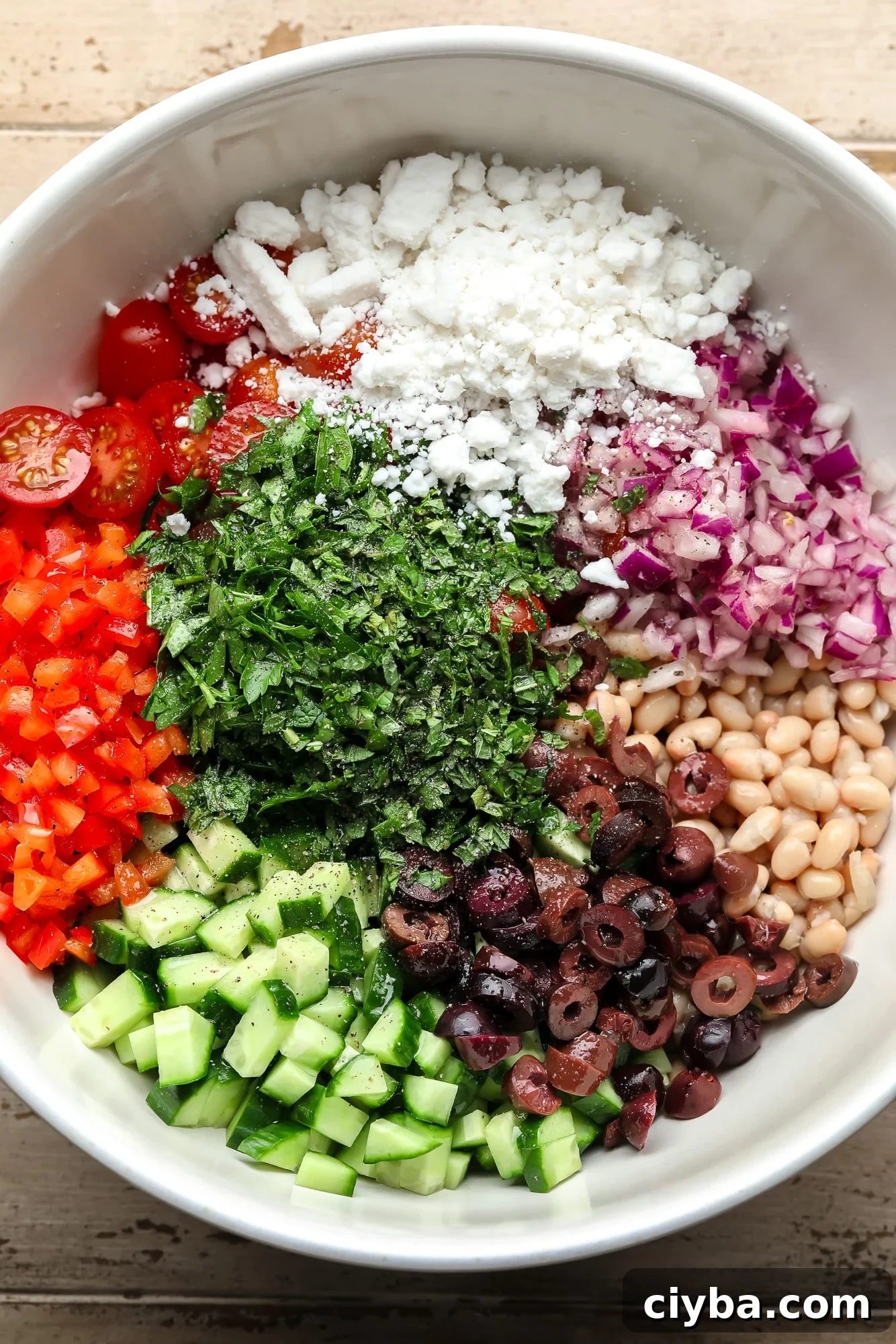 the ingredients for white bean salad in a large white bowl.