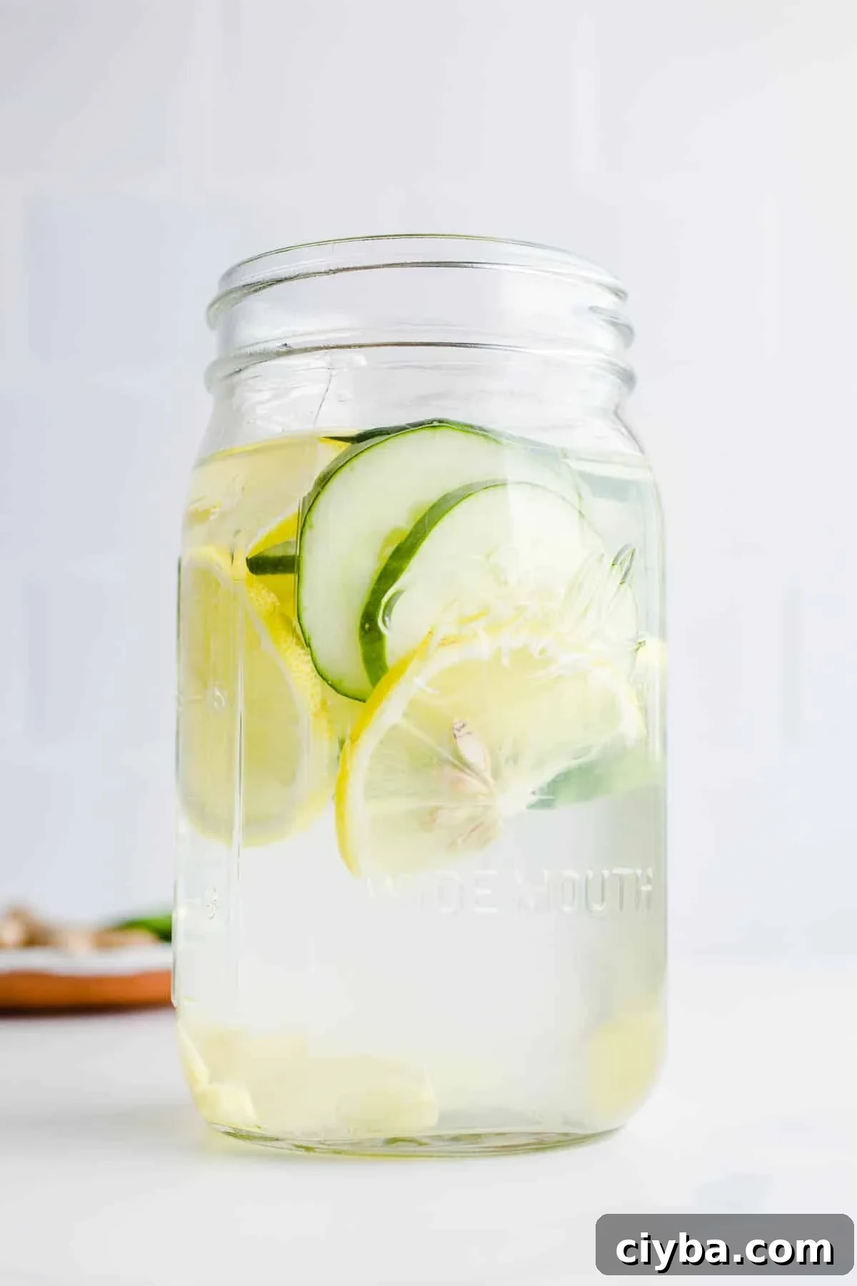 Slices of cucumber, lemon, and ginger in a mason jar.