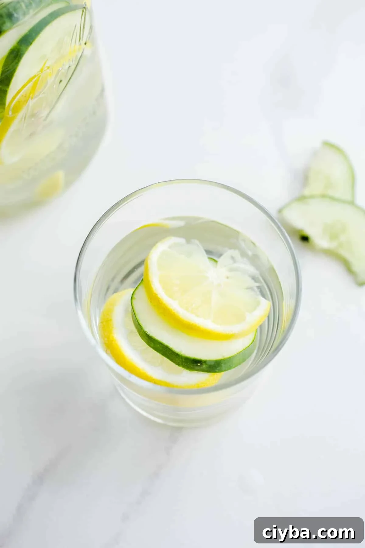 A glass with citrus and cucumber slices.