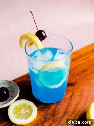 Blue lagoon cocktail with a lemon slice and cherry.