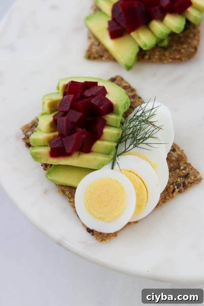Toast with sliced egg, avocado and pickled beets on a plate