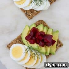 Toast with sliced egg, avocado and pickled beets on a plate