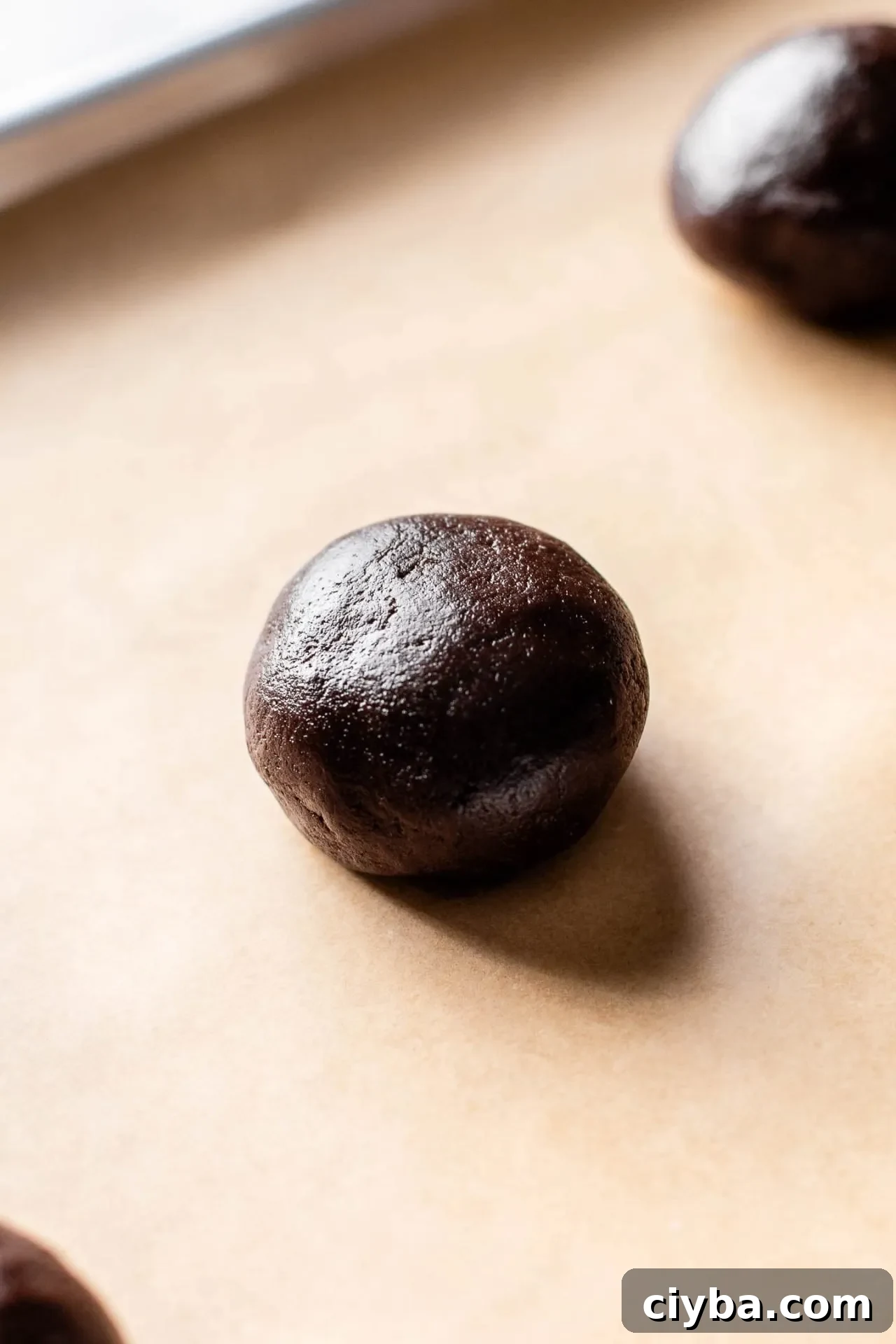 Nutella stuffed chocolate cookie dough ball on parchment lined baking sheet