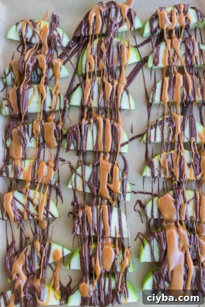 sliced apples on parchment paper drizzled with caramel and melted chocolate 