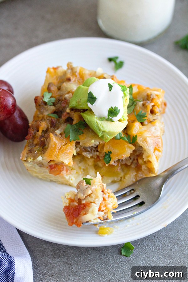 A piece of mexican breakfast casserole on a white plate with a bite on a fork sitting on the plate