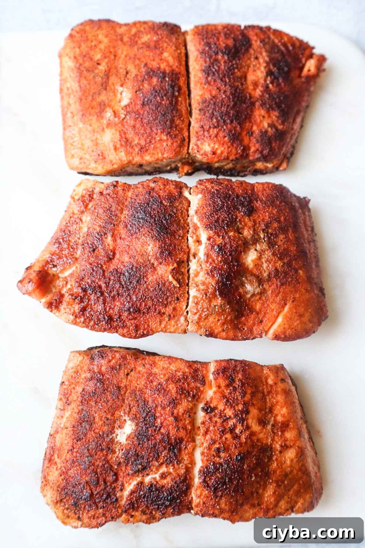 white cutting board with 3 cooked cajun salmon filets