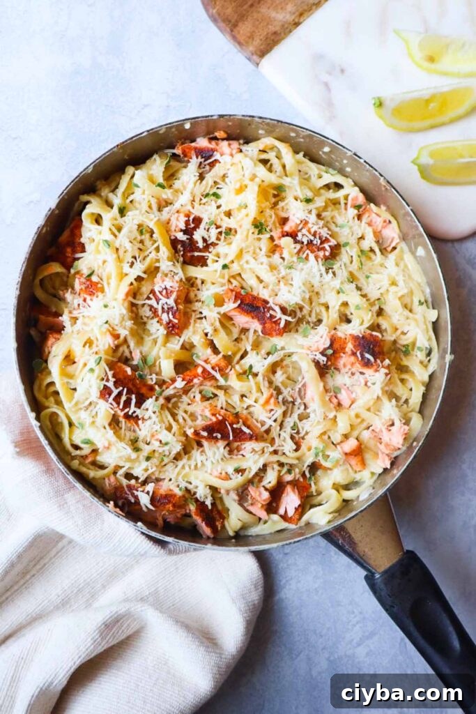 skillet with fettuccine alfredo topped with parmesan and cajun salmon