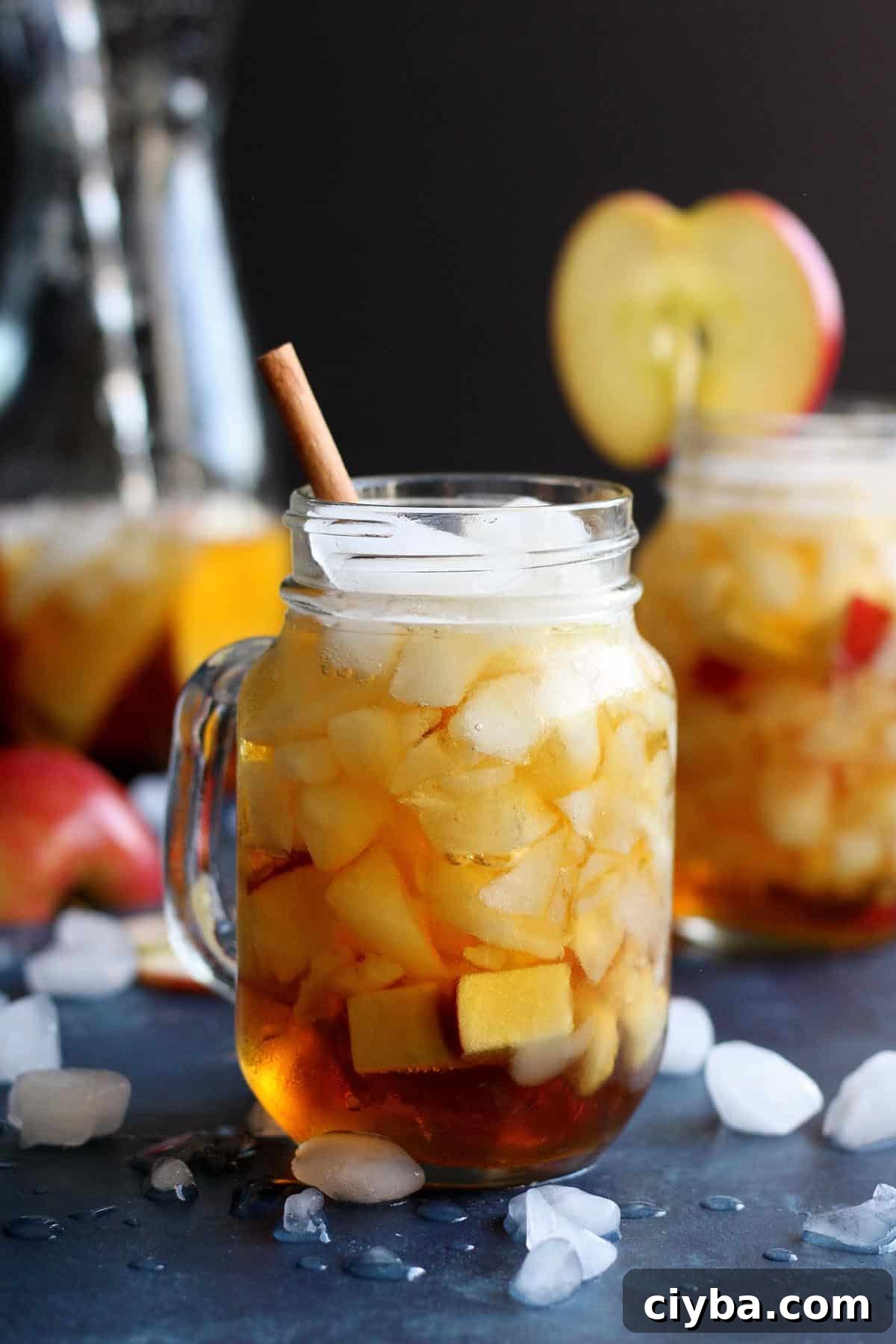 Autumn Pimm’s Cup Cocktail Recipe for Cozy Evenings 2 An apple Pimm's cup cocktail with a cinnamon stick in the from and one with a slice of apple in the back.