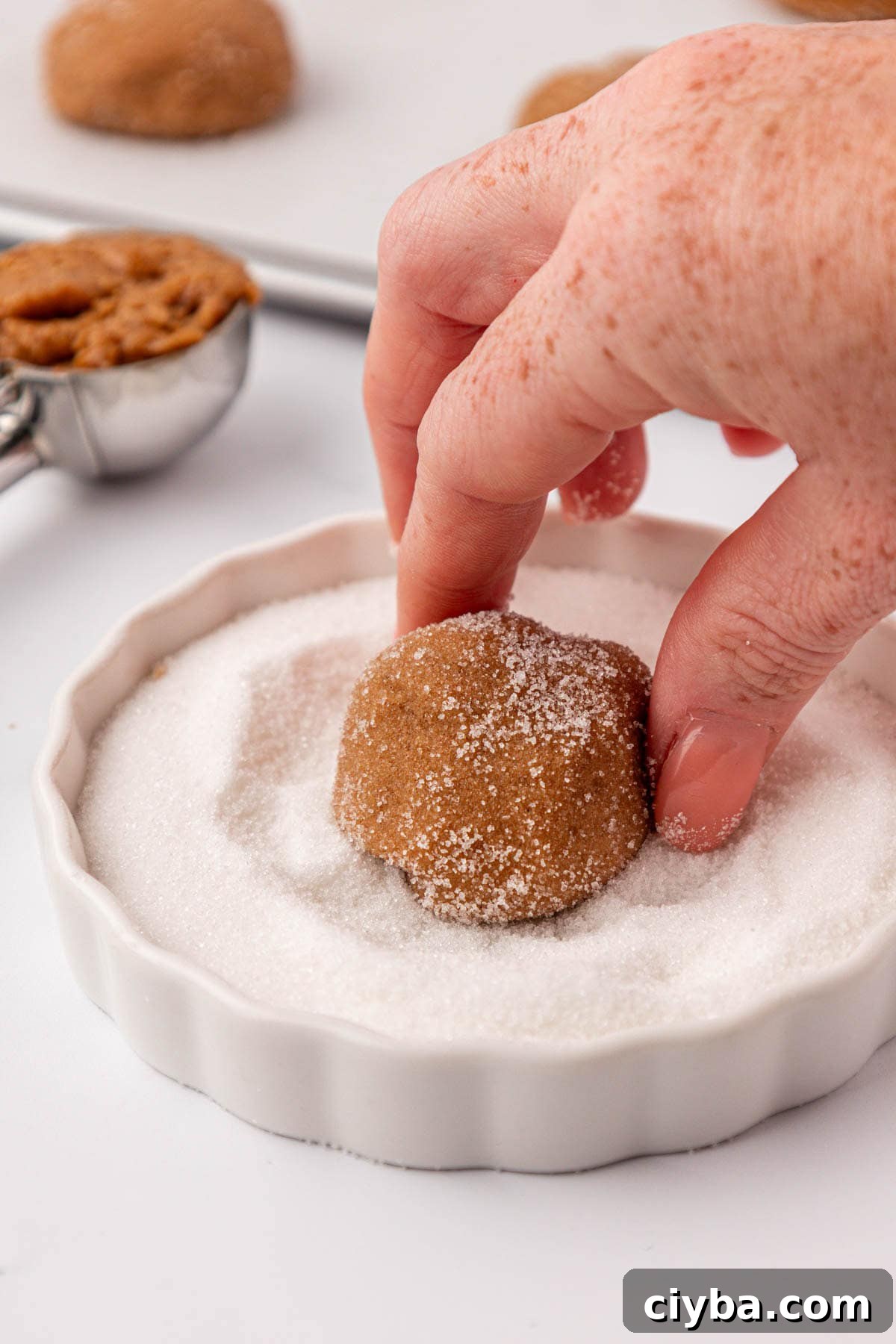 dipping a cookie dough ball into sugar