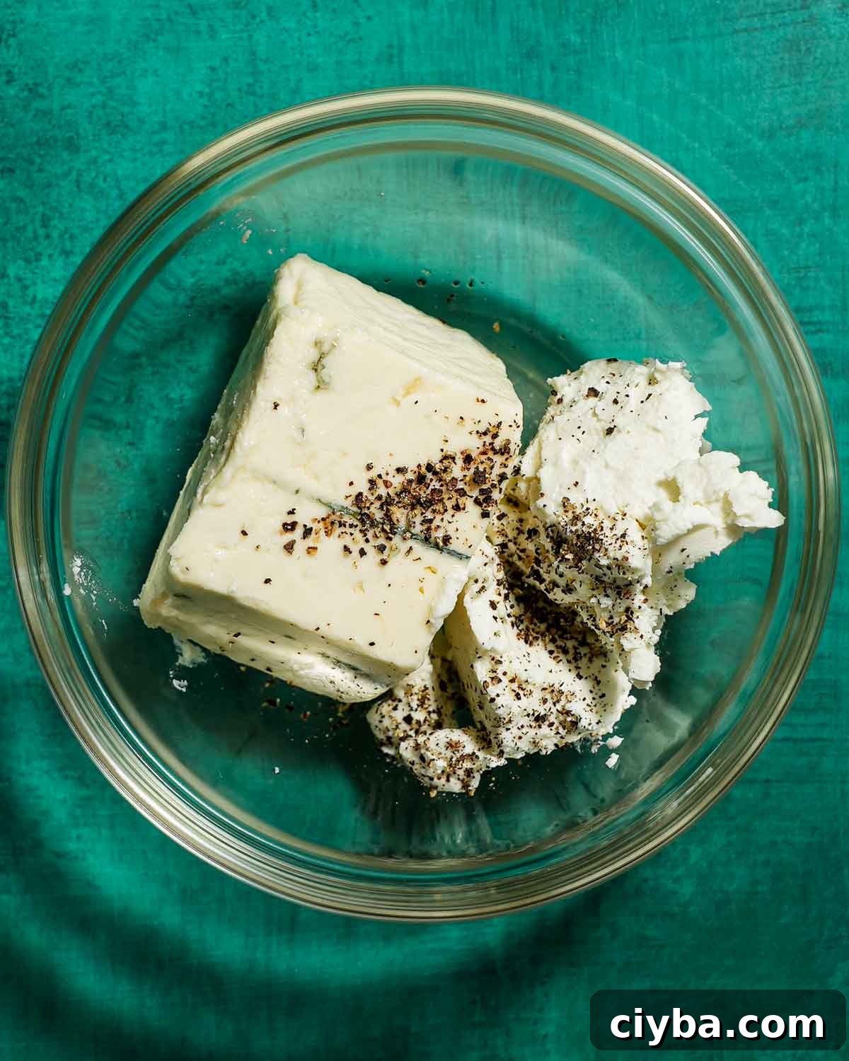A bowl of blue cheese and goat cheese ready to be stuffed in green olives.