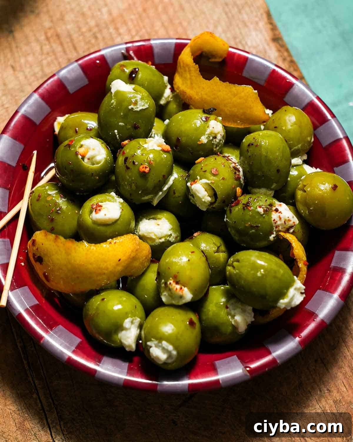 A small mixing bowl of stuffed blue cheese green olives on a cutting board.