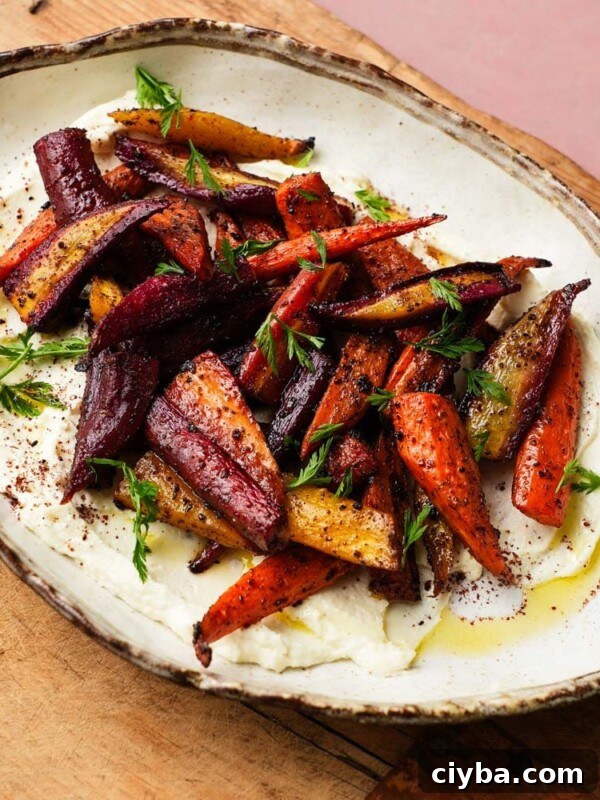 Roasted carrots with honey, sumac, and ricotta garnished with fresh herbs.