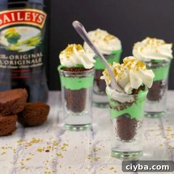 10 Irresistible Baileys Dessert Recipes for St. Patrick’s Day 3 Irish cream dessert shots with a bottle of irish cream in the background, on a white faux surface