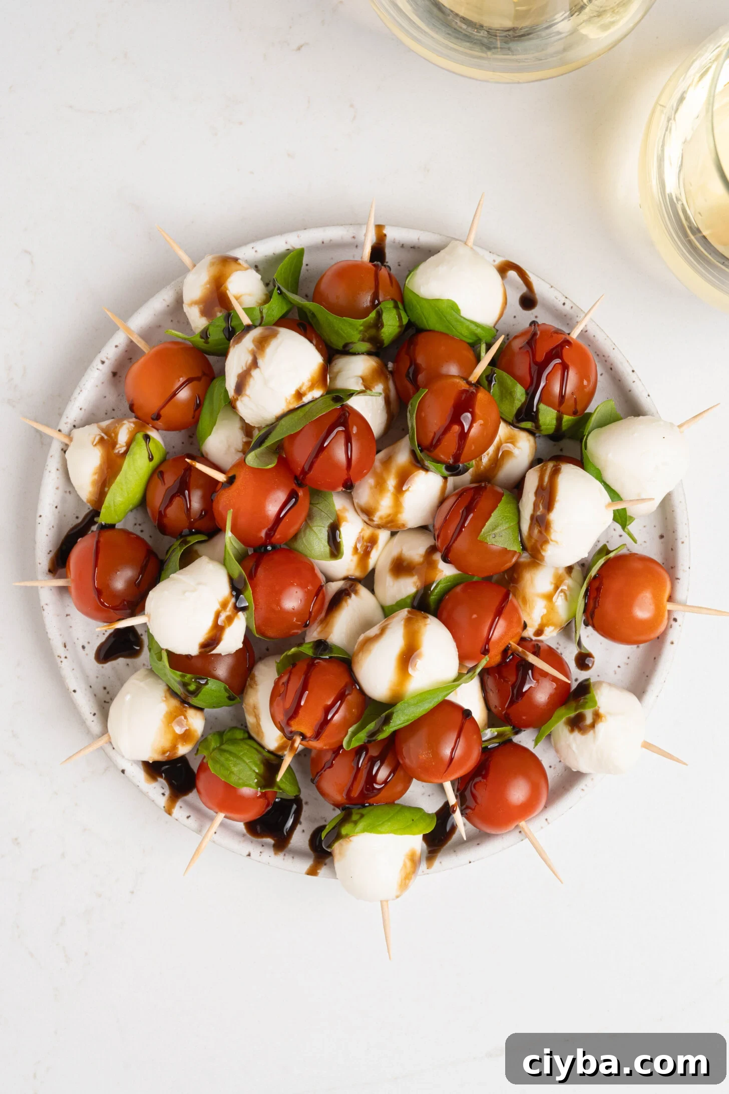 Caprese Skewers with Balsamic Glaze — Tomato, Mozzarella & Basil 3 A plate of caprese salad skewers.