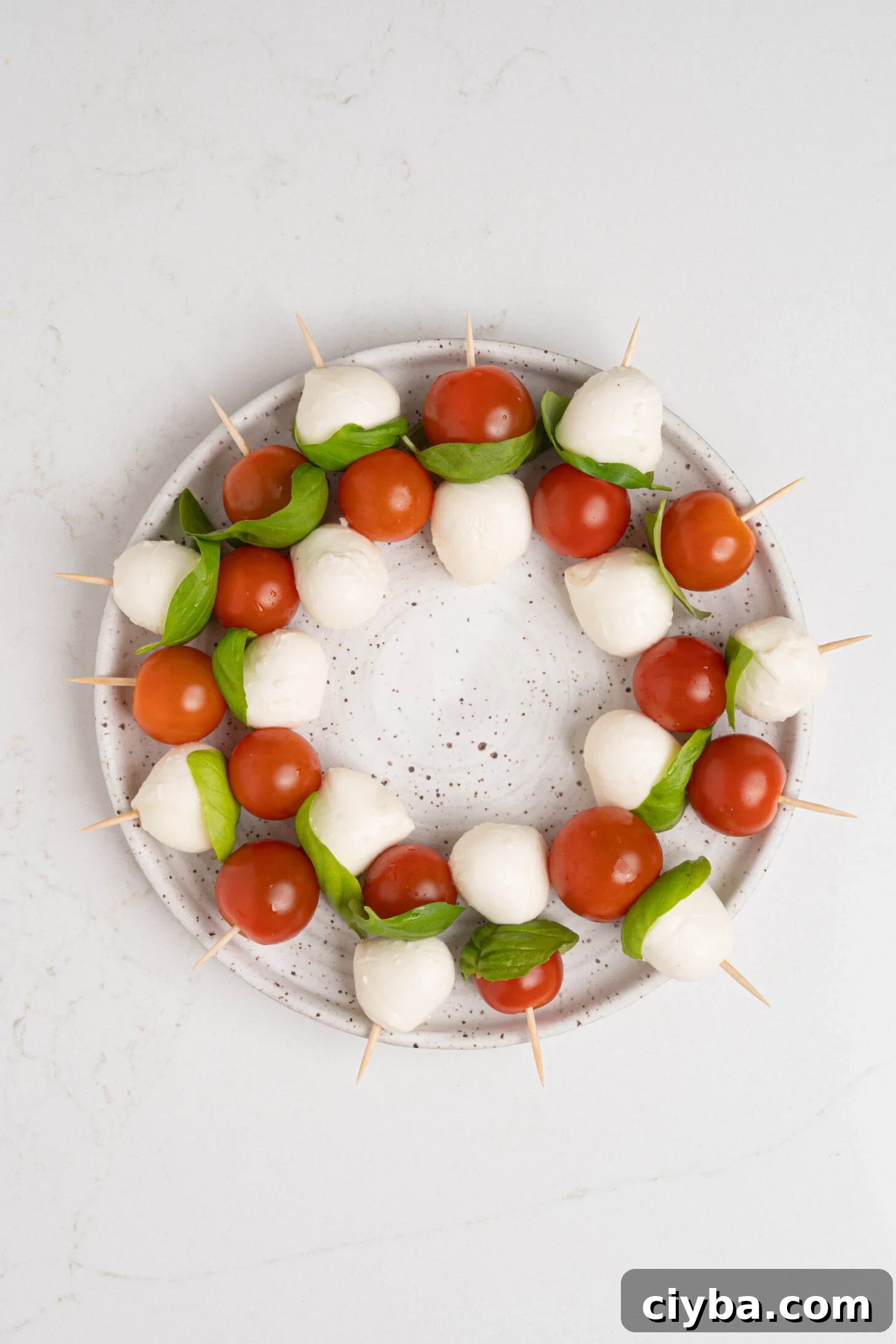 Caprese Skewers with Balsamic Glaze — Tomato, Mozzarella & Basil 6 A plate of caprese salad skewers.