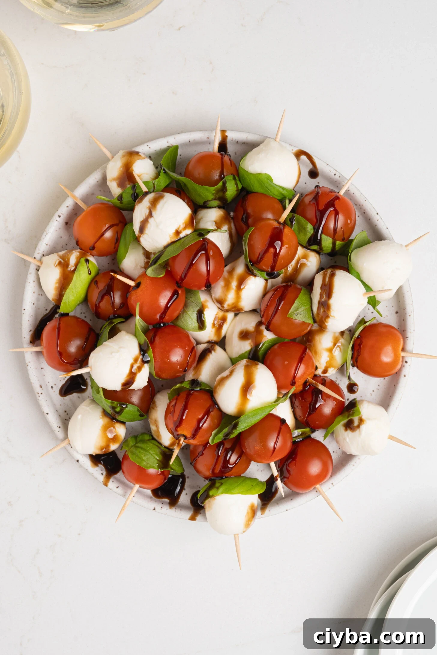 Caprese Skewers with Balsamic Glaze — Tomato, Mozzarella & Basil 7 A plate of caprese salad skewers.
