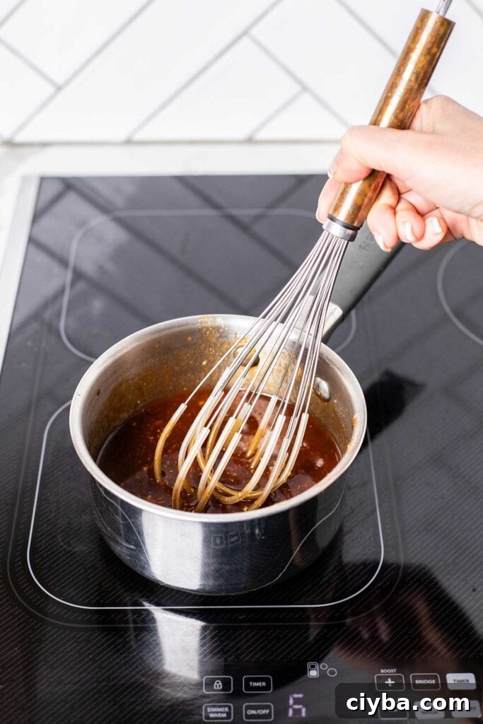 A saucepan with the ingredients for honey bbq sauce recipe being whisked until smooth.