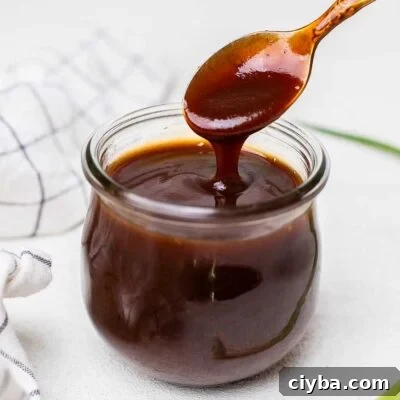 A thick honey bbq sauce shown in a jar next to a hand towel.
