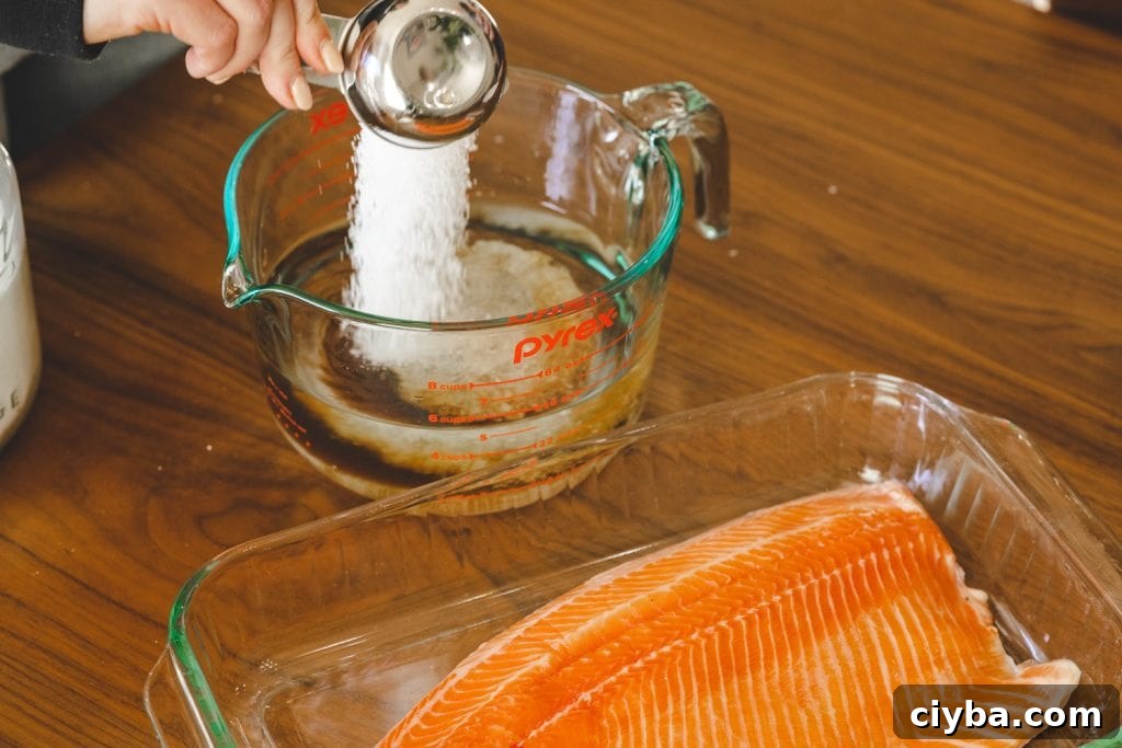 Salt being poured into a glass dish for smoked salmon brine.