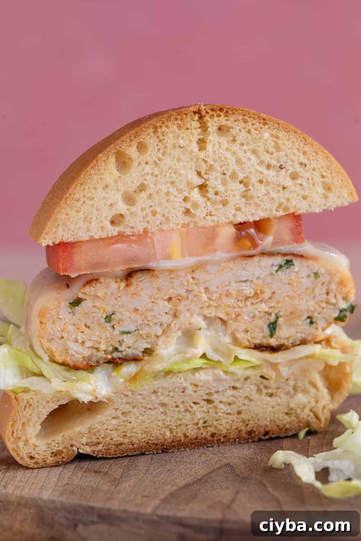 Cross section of a gluten free chicken burger in a bun cut in half.