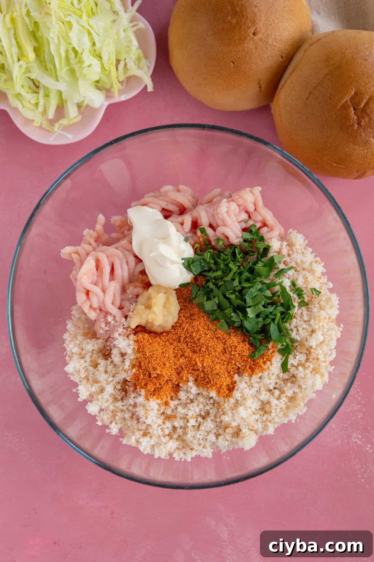 Process shot for chicken mince burgers showing the ingredients added to a glass mixing bowl.